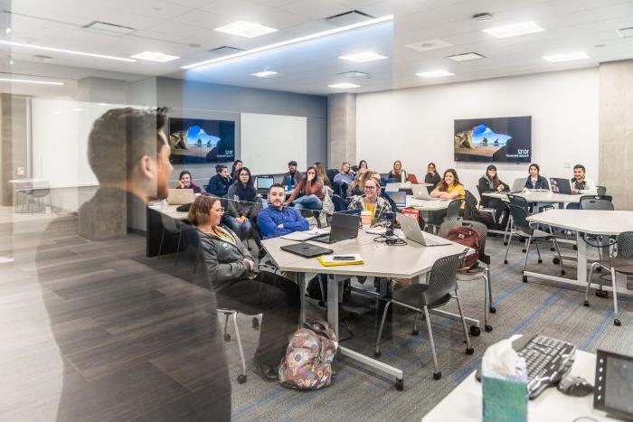 a photo of students in a classroom taken from outside of a glass wall.