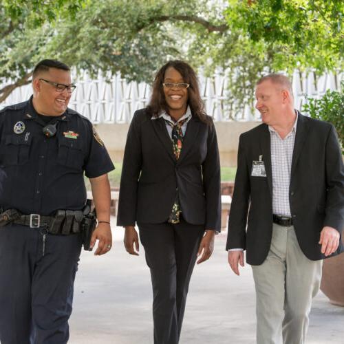 Three professionals walking, smiling, and talking to each other.