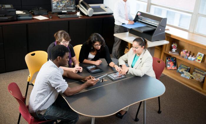 A group of student sitting at a table working on a project.